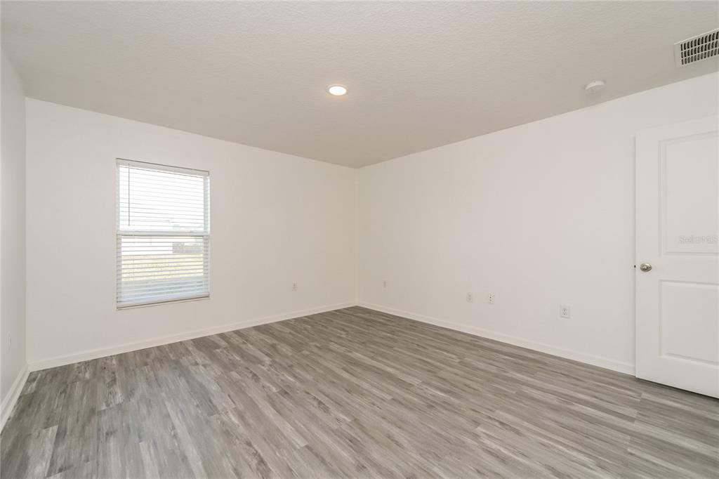 1477 Lucerne Loop Road Northeast Winter Haven, FL 33881 - Photo 9 of 15 an empty room with wooden floor and windows