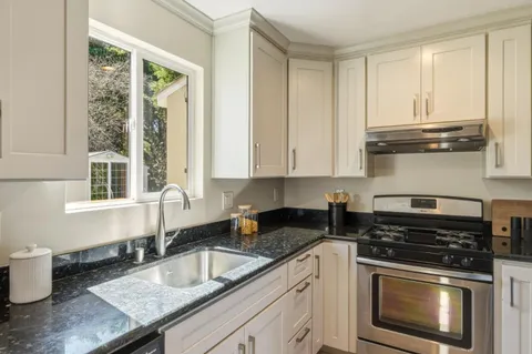 a kitchen with granite countertop a stove sink and cabinets