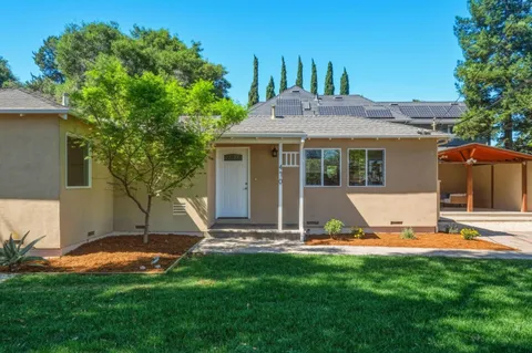 a view of a white house with a big yard potted plants and large tree