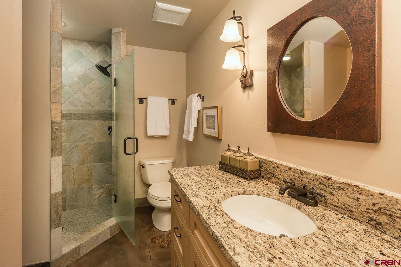 304 Peak Trail Hesperus, CO 81326 - Photo 32 of 35 a bathroom with a granite countertop toilet a sink and a mirror