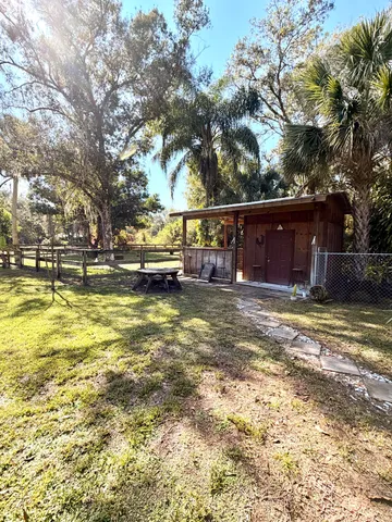 a view of a house with a yard and large trees