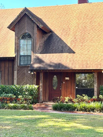 a front view of a house with a yard and potted plants
