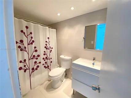 a bathroom with a toilet sink and shower curtain