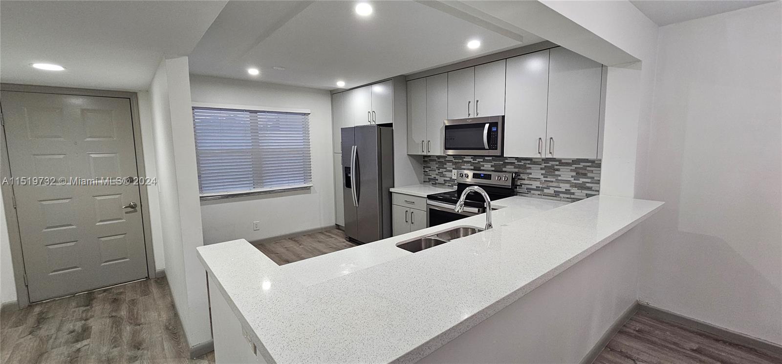 a kitchen with kitchen island a sink stainless steel appliances and counter space