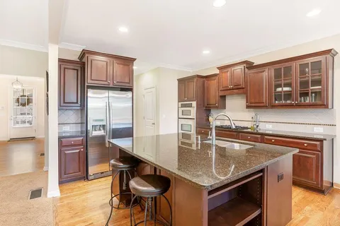a kitchen with stainless steel appliances granite countertop a kitchen island a stove and a sink
