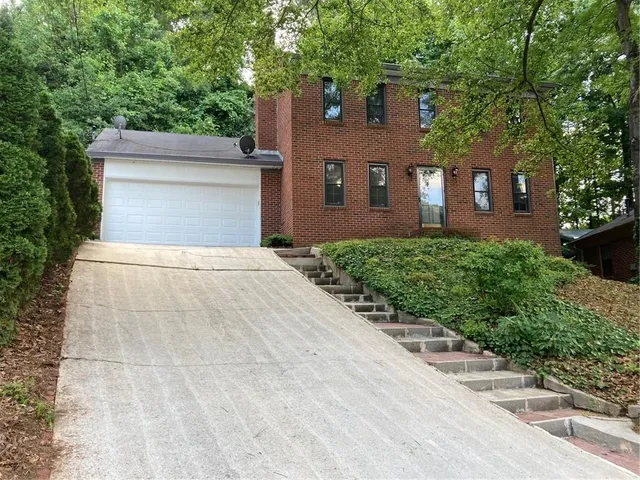 a front view of a house with yard and trees
