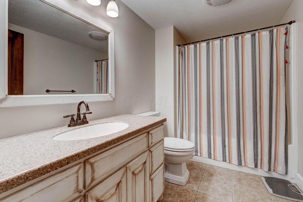 4045 Russell Road Mount Gilead, OH 43338 - Photo 38 of 74 • Ceramic tile flooring • Gray painted walls • Amish cabinets • Single bowl sink • Shower/tub combination