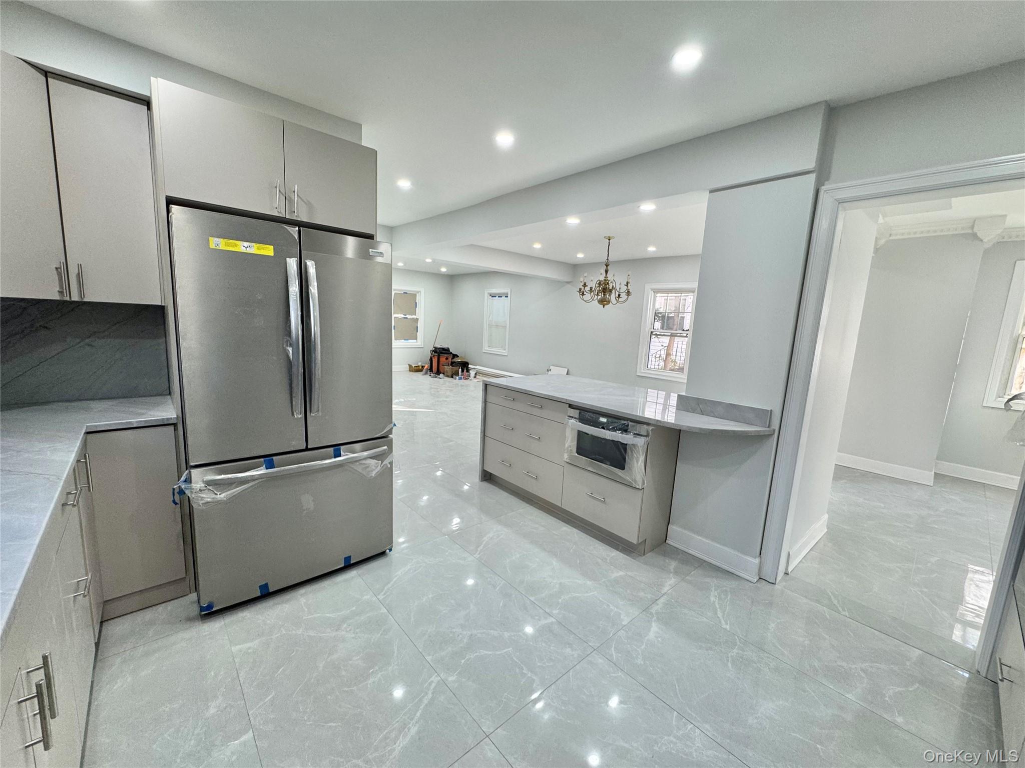 32 A Berkshire Road Great Neck, NY 11023 - Photo 12 of 38 Kitchen with appliances with stainless steel finishes, gray cabinets, light marble finish floors, pendant lighting, and light stone counters