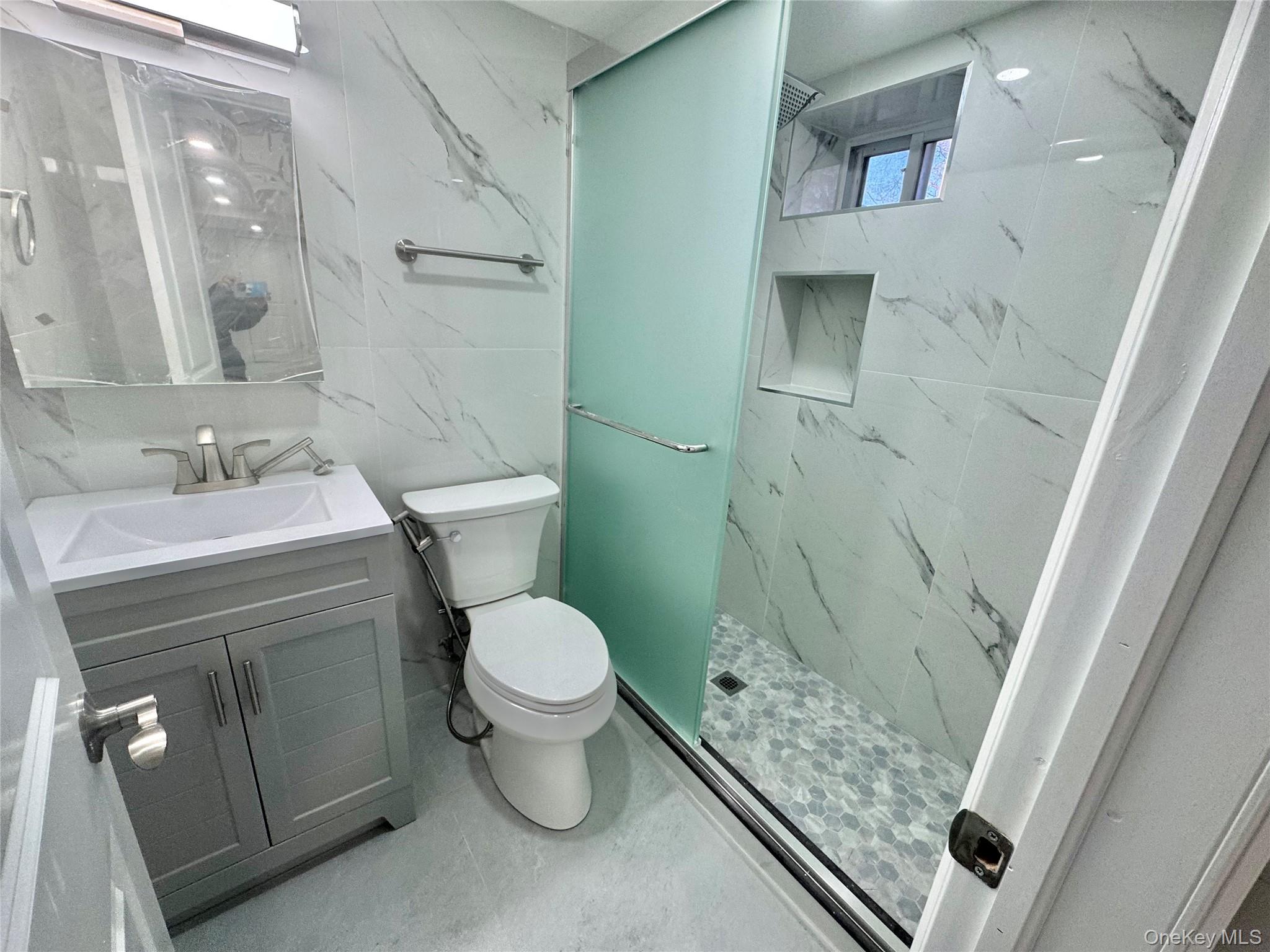 32 A Berkshire Road Great Neck, NY 11023 - Photo 28 of 38 Bathroom in Basement featuring vanity, a marble finish shower, and tile walls