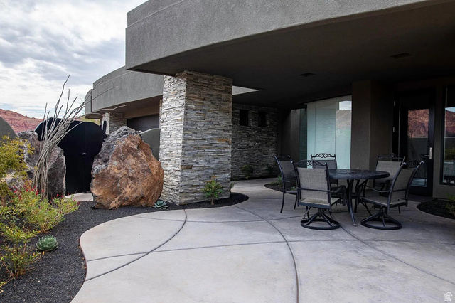 1500 Split Rock, Unit 150 Ivins, UT 84738 - Photo 12 of 14 Expansive concrete patio area beneath a covered overhang, featuring a stacked stone column and textured exterior wall