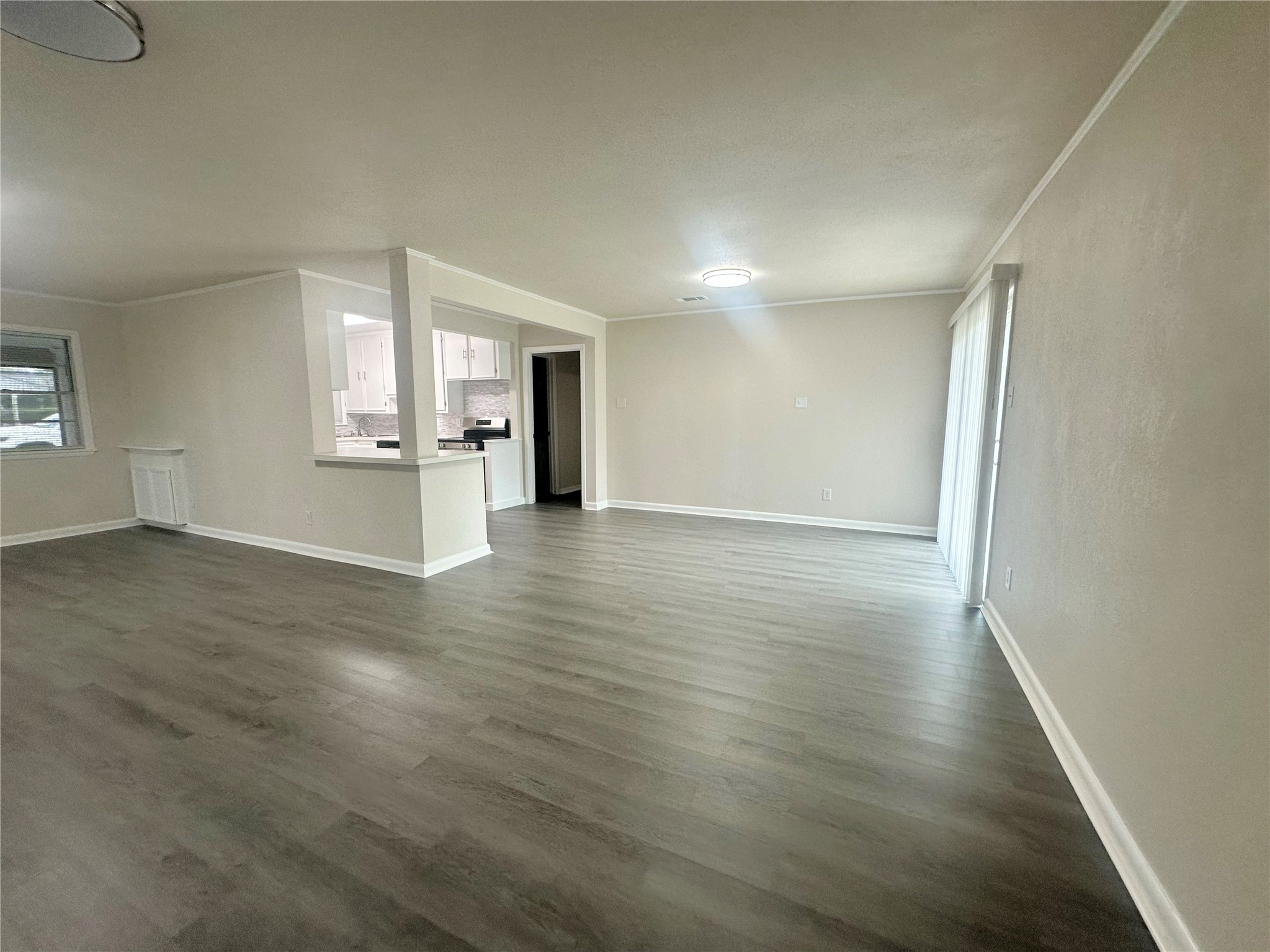 130 Bay Ridge Drive Baytown, TX 77523 - Photo 8 of 20 This photo shows a spacious, open-concept living area with light walls and modern flooring. It features a large window for natural light and a view into a sleek kitchen with contemporary design elements. Ideal for comfortable living and entertaining.