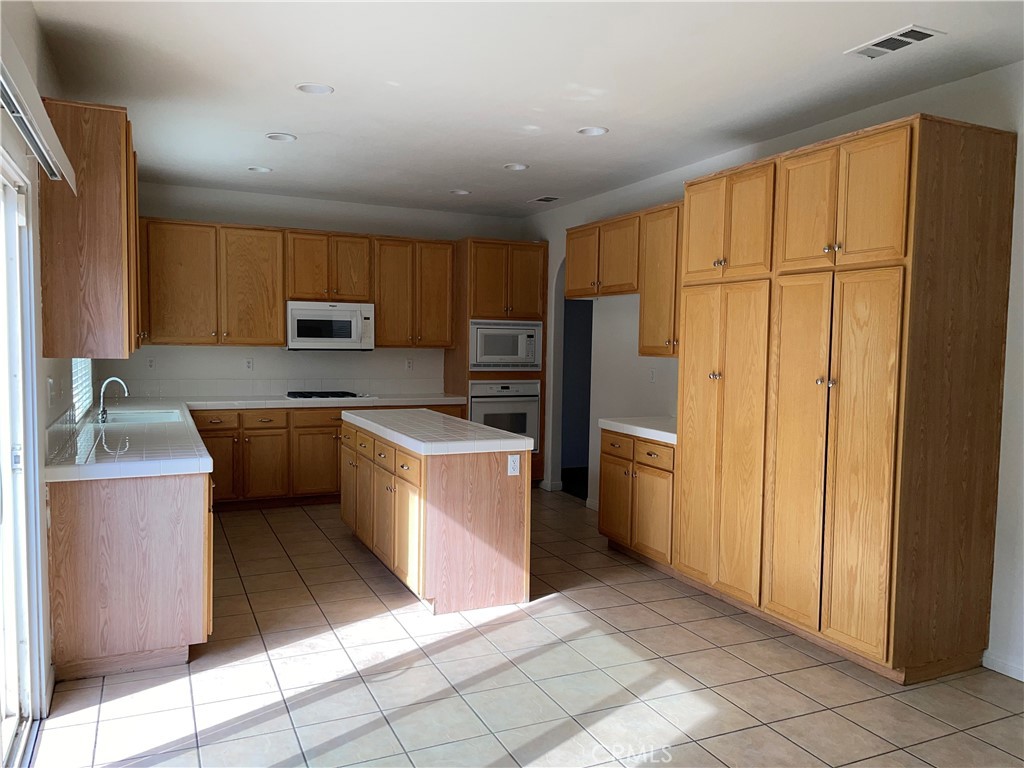 12661 Luna Road Victorville, CA 92392 - Photo 9 of 20 a kitchen with a refrigerator a stove top oven and a sink