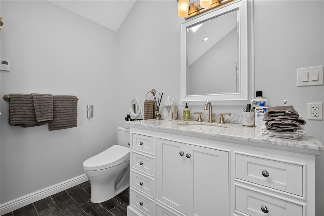 6467 Abbey Road Wind Gap, PA 18091 - Photo 24 of 46 A refined bathroom featuring a contemporary vanity with a gleaming countertop, an elegant basin, and dark wood-look tile flooring.