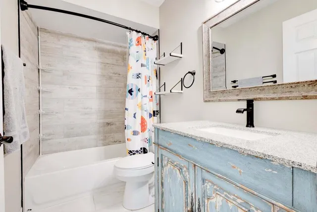 a bathroom with a granite countertop sink a toilet and shower
