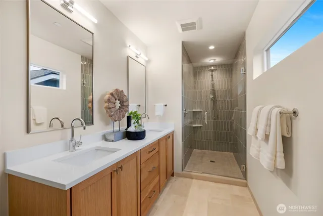 a bathroom with a double vanity sink a shower and a mirror