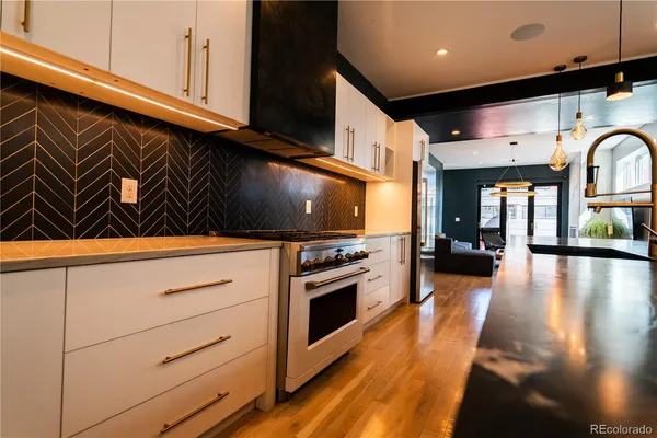 a kitchen with stainless steel appliances granite countertop a sink a stove and a wooden floor