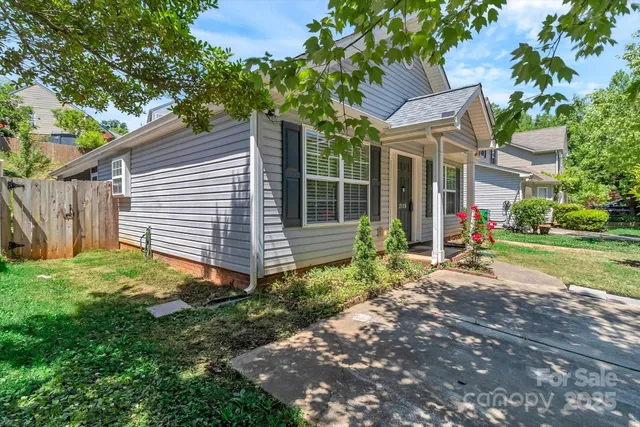 a view of a white house with a small yard and large tree