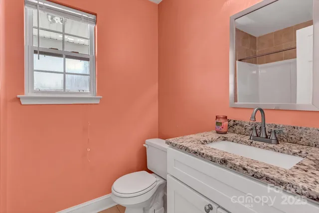 a bathroom with a granite countertop toilet sink and mirror