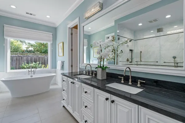 a bathroom with double vanity sinks a mirror and a bathtub