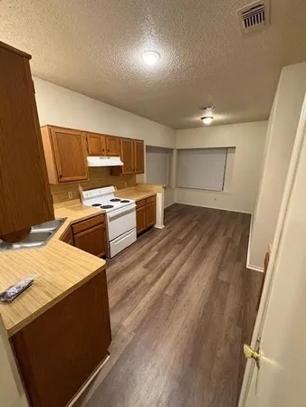a large kitchen with a wooden floor and stainless steel appliances
