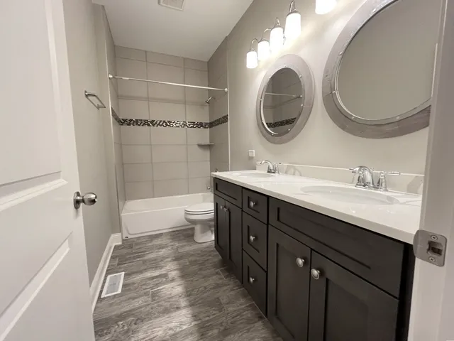 a bathroom with a double vanity sink mirror and bathtub