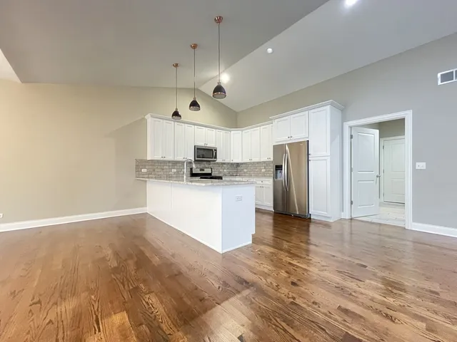 a large kitchen with cabinets and wooden floor