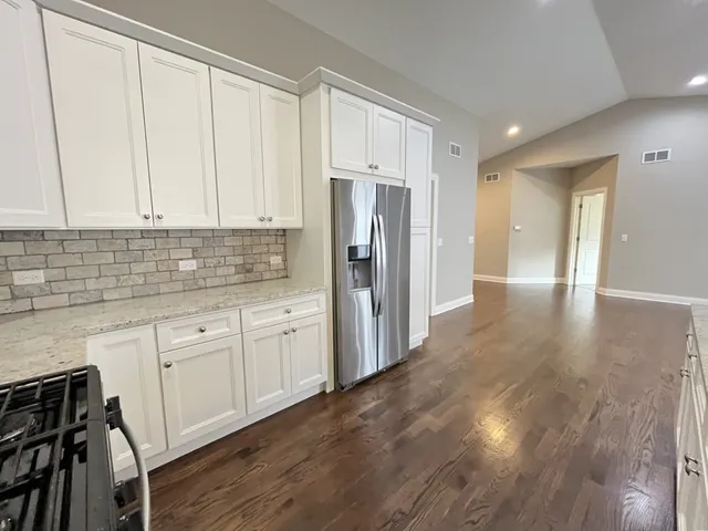 a kitchen with stainless steel appliances granite countertop a refrigerator sink and white cabinets