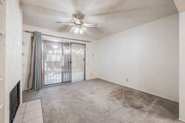 a view of an empty room with chandelier fan