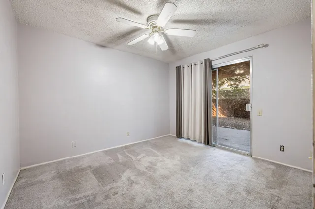 an empty room with windows and fan