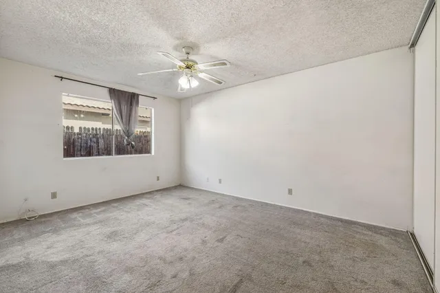 an empty room with a window and a fan