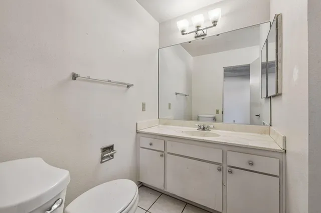 a bathroom with a granite countertop toilet sink and mirror