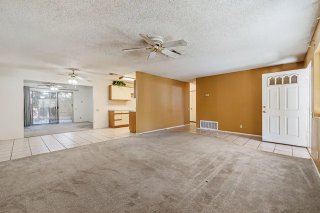 a view of a livingroom with a chandelier fan and windows
