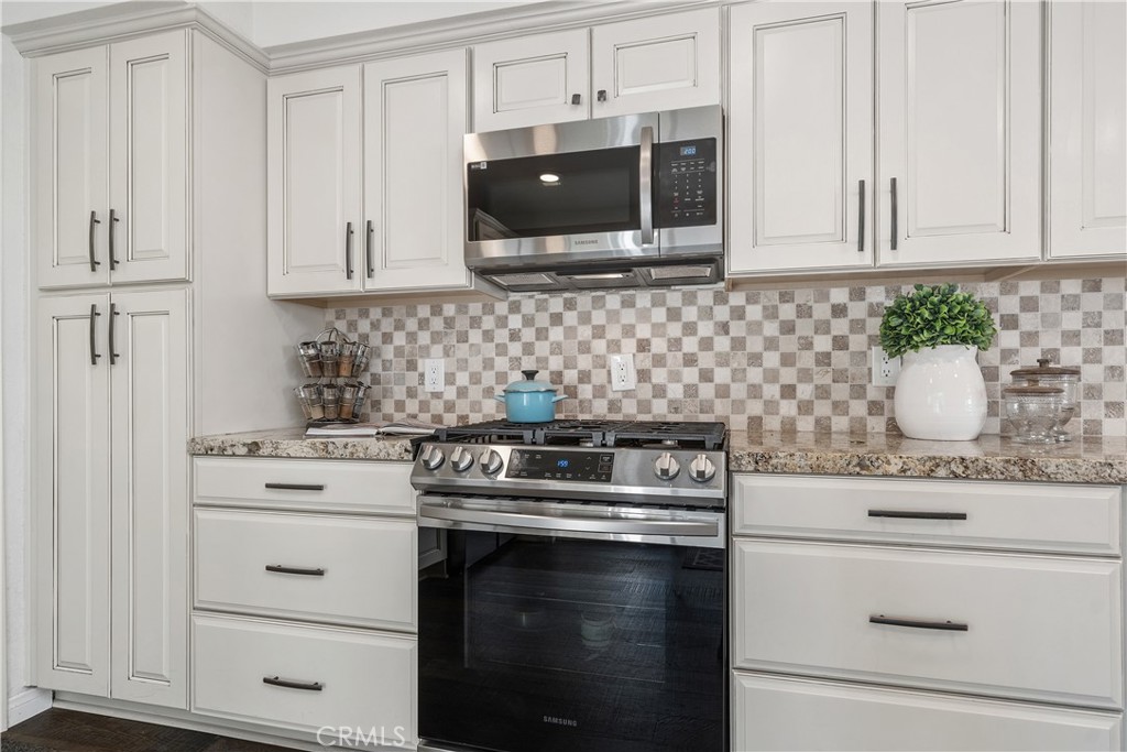 1041 Tustin Pines Way Tustin, CA 92780 - Photo 17 of 32 a kitchen with stainless steel appliances granite countertop white cabinets and black stove top oven with granite countertops