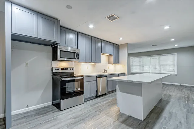 a kitchen with stainless steel appliances granite countertop a stove top oven a sink dishwasher and a refrigerator