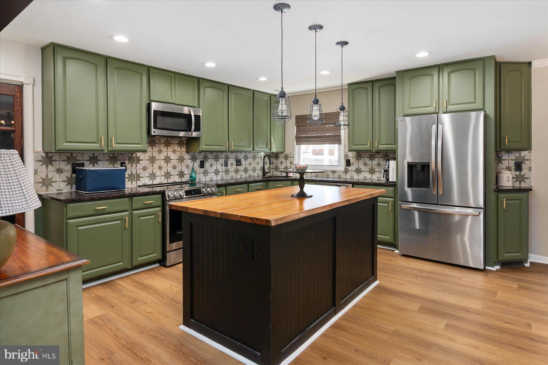 7801 Harle Road Pasadena, MD 21122 - Photo 28 of 64 a kitchen with stainless steel appliances kitchen island granite countertop a refrigerator a sink dishwasher a oven with wooden cabinets and a wooden floor