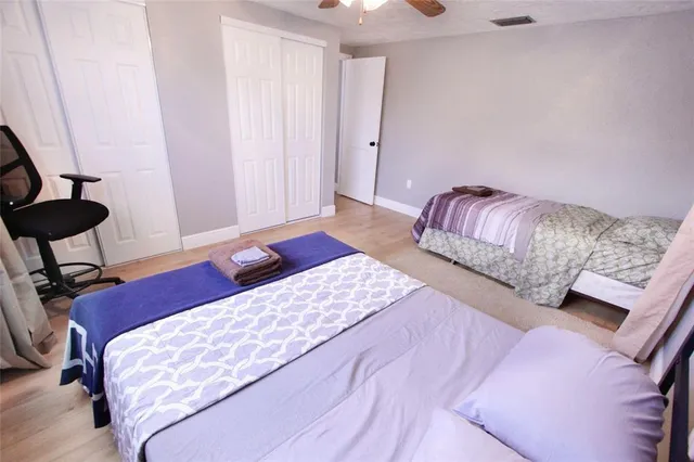 a bedroom with a bed a chair and potted plant on a dresser