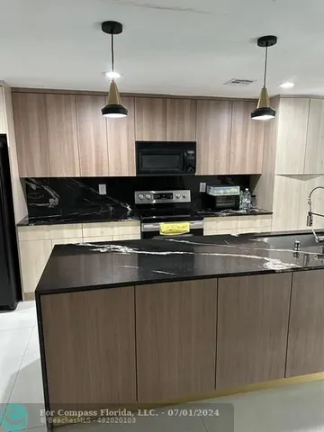 a kitchen with stainless steel appliances granite countertop a sink a stove a microwave and a refrigerator