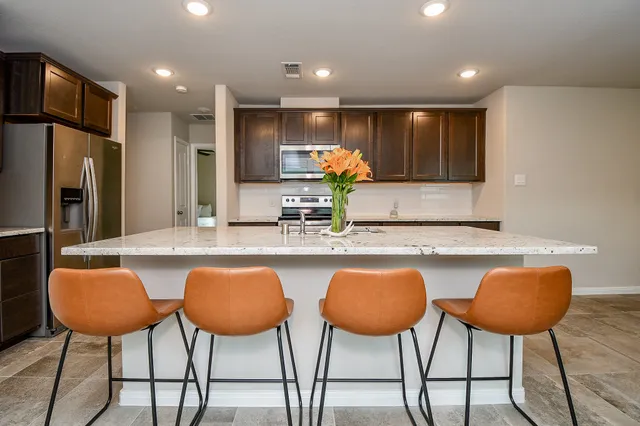 a kitchen with stainless steel appliances granite countertop a table and chairs in it