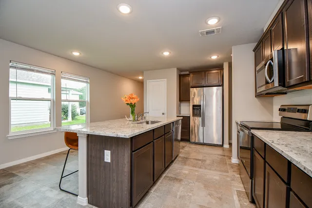 a kitchen with kitchen island granite countertop a sink stove and refrigerator