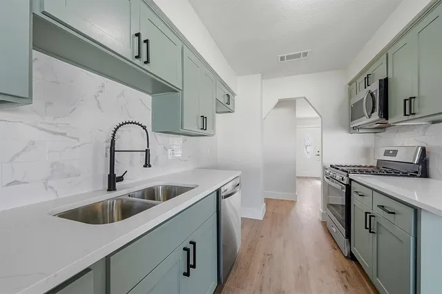 a kitchen with stainless steel appliances a sink stove and cabinets