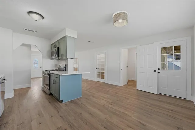 a kitchen with stainless steel appliances wooden floors and view living room