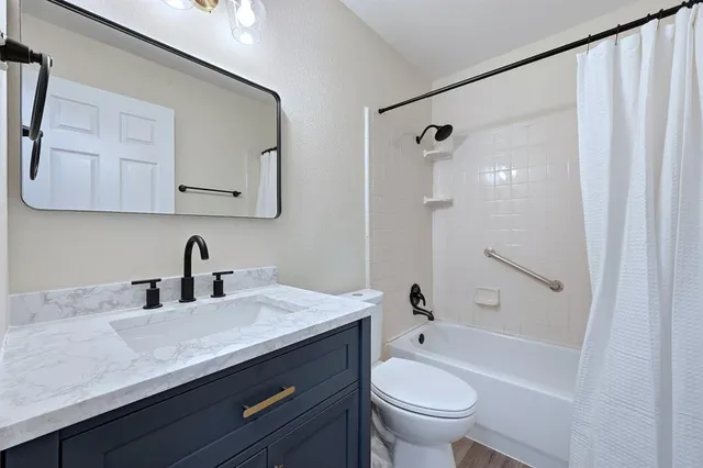 a bathroom with a granite countertop sink a toilet and shower
