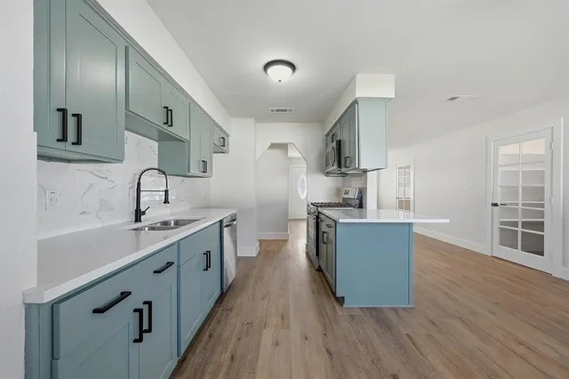 a kitchen with stainless steel appliances a sink cabinets and wooden floor