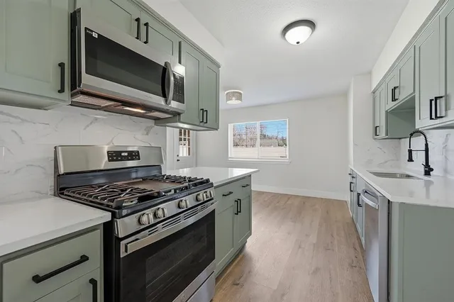 a kitchen with stainless steel appliances a stove a sink and a microwave