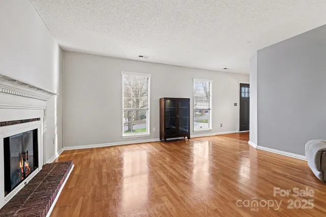 a view of an empty room with a fireplace and wooden floor