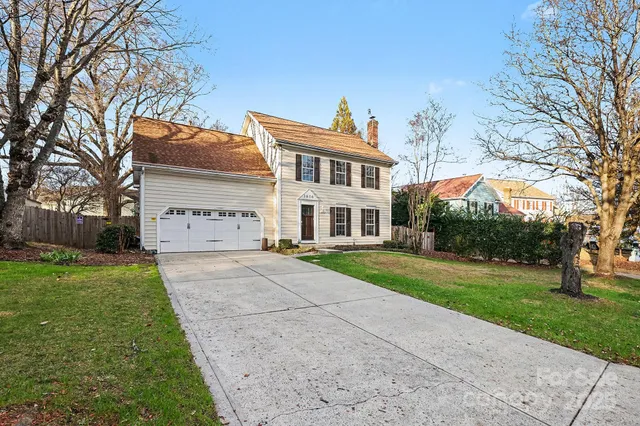 a view of a white house with a yard and large tree