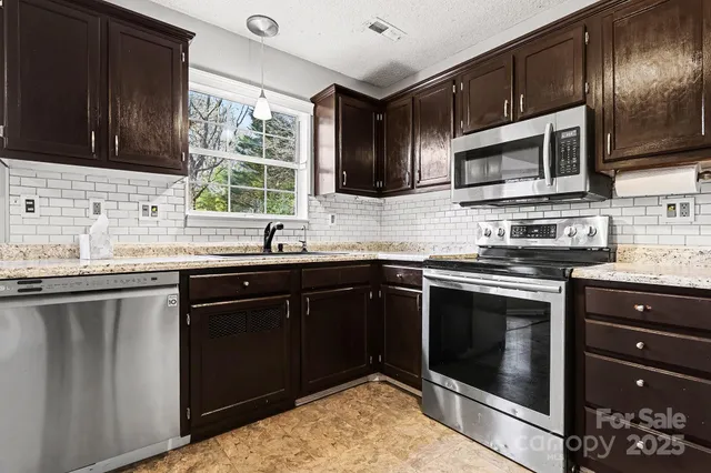 a kitchen with stainless steel appliances granite countertop a sink stove and microwave