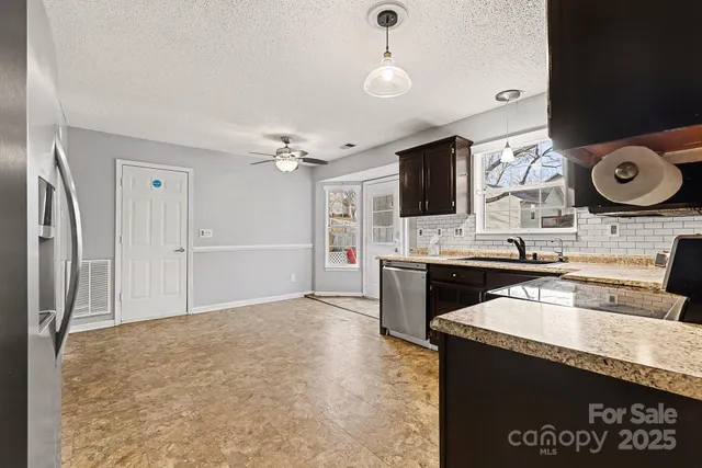 a kitchen with granite countertop a sink cabinets and stainless steel appliances