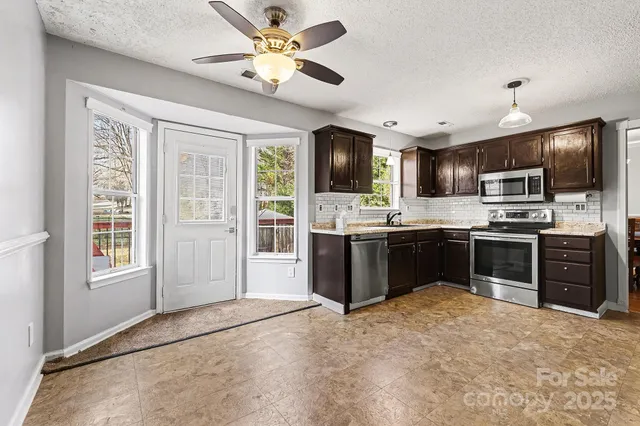 a kitchen with stainless steel appliances kitchen island granite countertop a refrigerator stove top oven and sink