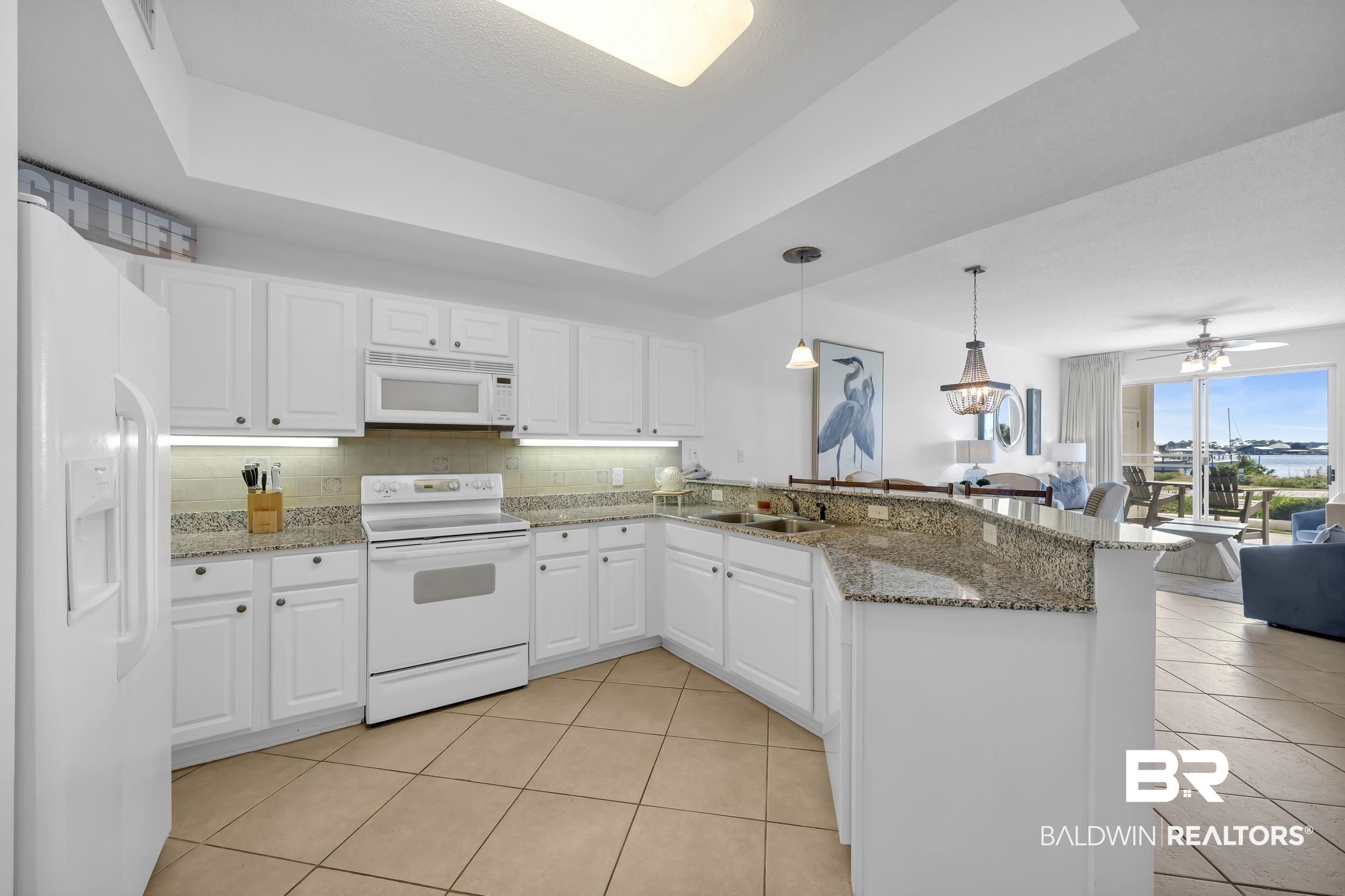27282 Canal Road, Unit 104 Orange Beach, AL 36561 - Photo 79 of 79 Kitchen with a tray ceiling, a peninsula, white appliances, pendant lighting, and open floor plan